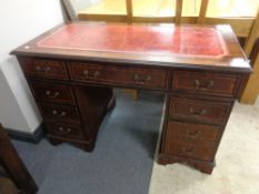 A reproduction inlaid mahogany twin pedestal nine drawer writing desk with tooled leather inset