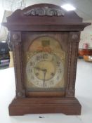 An oak mantel clock with brass and silvered dial