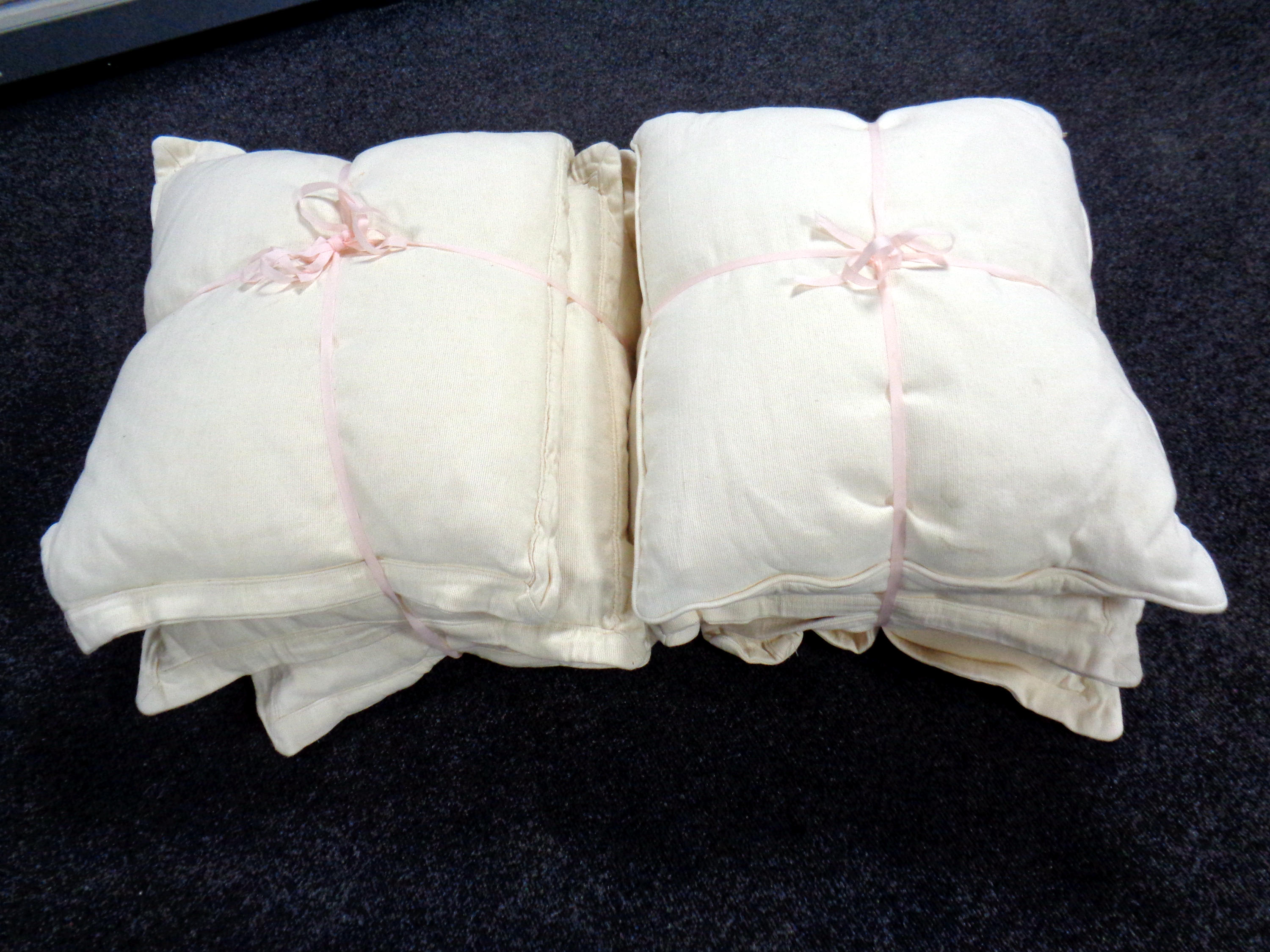 Two bundles of cream contemporary cushions.