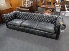 A black leather Chesterfield three-seater club settee