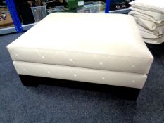 An oversized footstool upholstered in cream leather.