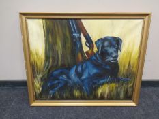 J E Wigston : A black labrador and shotguns beside a tree, oil-on-board, in gilt frame.