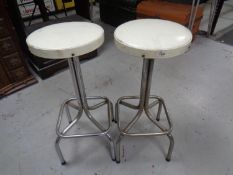 A pair of 20th century tubular metal cream vinyl upholstered bar stools.