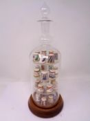 A set of 28 Royal Crown Derby china thimbles on display stand in the form of a decanter.