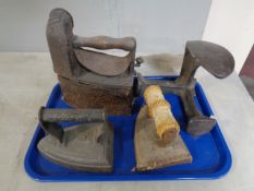 A tray containing a cast iron cobblers last together with a pair of flat irons.