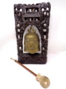 A brass Asian temple bell on a carved hardwood stand with beater.