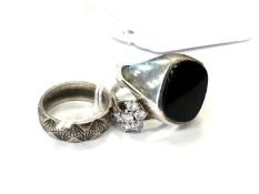 Three silver rings including a black onyx signet ring.