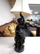 A patinated metal figural table lamp in the form of a female figure,