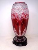 A Bohemian ruby tinted glass vase (height 40cm) on a black glass stand.