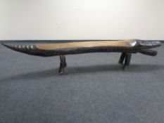 A carved hardwood bench in the form of a crocodile,