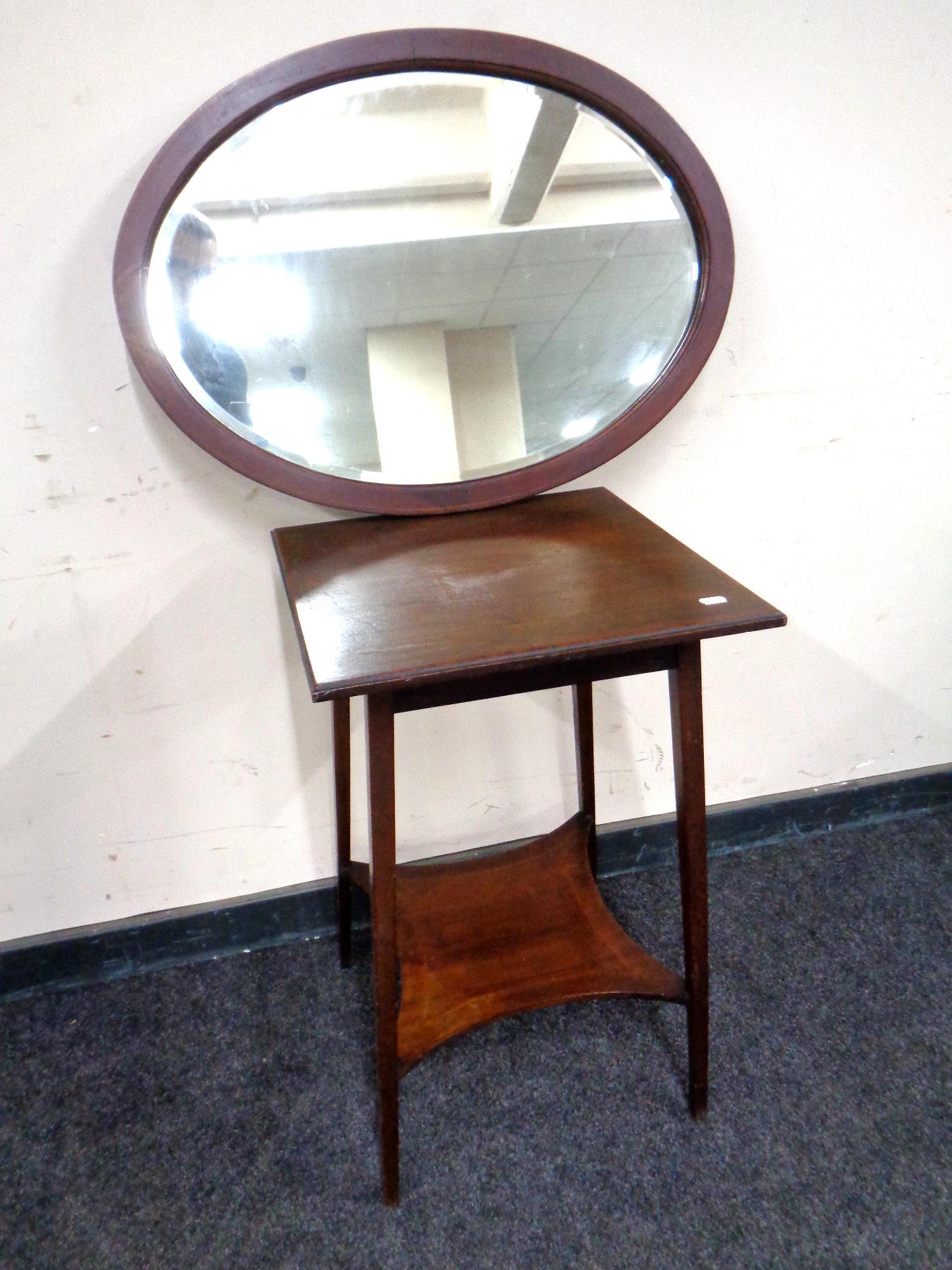 An Edwardian two tier occasional table together with an oval framed mirror.