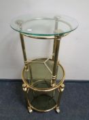 A brass two-tier smoked glass trolley with lift off tray together with a further brass and glass