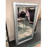 A contemporary mirror in a silvered frame, 79cm x 139cm.