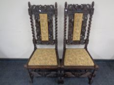 A pair of heavily carved oak barley twist hall chairs upholstered in a gold floral fabric.
