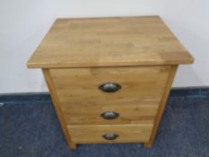 A contemporary oak three drawer bedside chest.