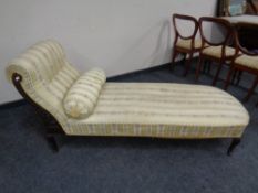 An Edwardian mahogany framed chaise longue upholstered in a gold striped fabric.