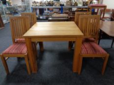 A contemporary oak square dining table together with a set of four rail back chairs.