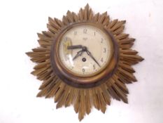 A gilt wood Art Deco Smiths 8 Day 4 Jewel Sunburst wall clock with key.