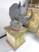 A concrete rhino head statue on a composite plinth,