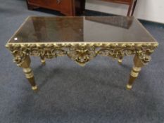 A decorative gilt smoked glass coffee table