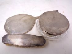 A silver-backed dressing table hand-mirror together with a silver-backed brush and a lidded jar,