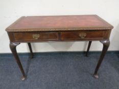 A mahogany two drawer writing table on pad feet with a red leather inset panel.