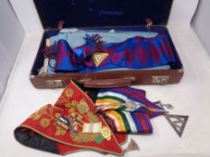 A leather case containing Freemason's regalia including sashes, bags and medals.