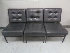 A set of three mid century reception chairs in black buttoned vinyl stamped Furniture Maintenance