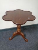 A clover leaf pedestal occasional table on claw and ball feet.
