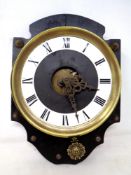 A continental brass cased wall clock with sun pendulum, mounted on a board.