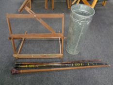 A folding wooden artists easel together with a metal stick pot containing three walking sticks.