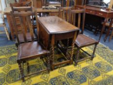 A 20th century oak barley twist drop leaf table together with a set of four chairs.