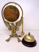 A brass dinner gong with beater on eagle stand together with a brass desk bell.