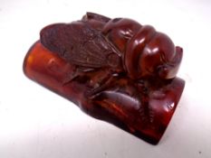 A carved resin figure of an insect on a branch.