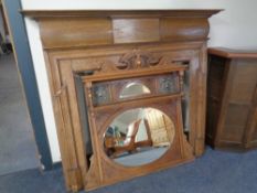 An Edwardian oak fire surround together with a similar Arts & Crafts overmantel mirror with inset