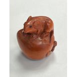 A carved fruitwood netsuke - rat seated on fruit