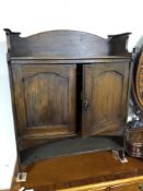 An Edwardian Arts and Crafts double door wall cabinet fitted internal drawers and shelves