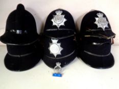 A box containing six policeman's helmets, three bearing Northumberland Constabulary badges.