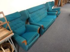 A mid-20th century G plan three piece wing-back lounge suite upholstered in a turquoise button