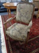 An antique French walnut armchair upholstered in tapestry fabric.