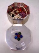 An octagonal plated trinket box containing a small quantity of costume jewellery.