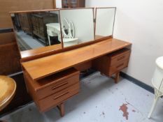 A 20th century teak Austin Suite knee-hole dressing table with triple mirror.