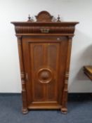 An antique continental oak cabinet fitted with internal shelves and drawer above with pillar column