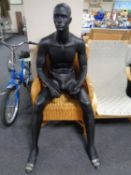 A male mannequin, seated.