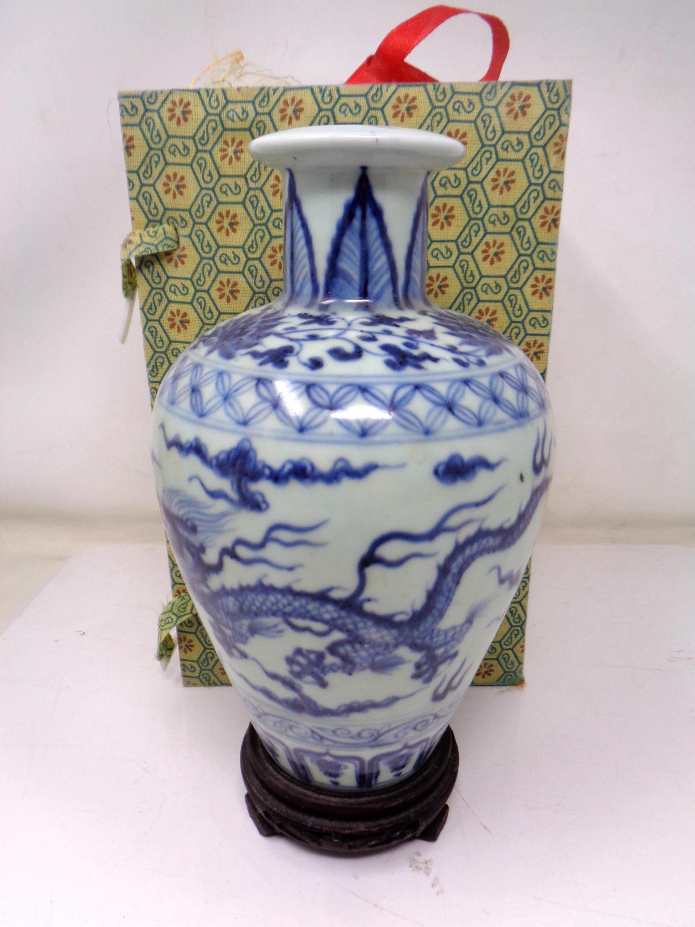 A Chinese blue and white porcelain baluster vase on carved wooden stand (height 21cm).