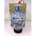 A Chinese blue and white porcelain baluster vase on carved wooden stand (height 21cm).