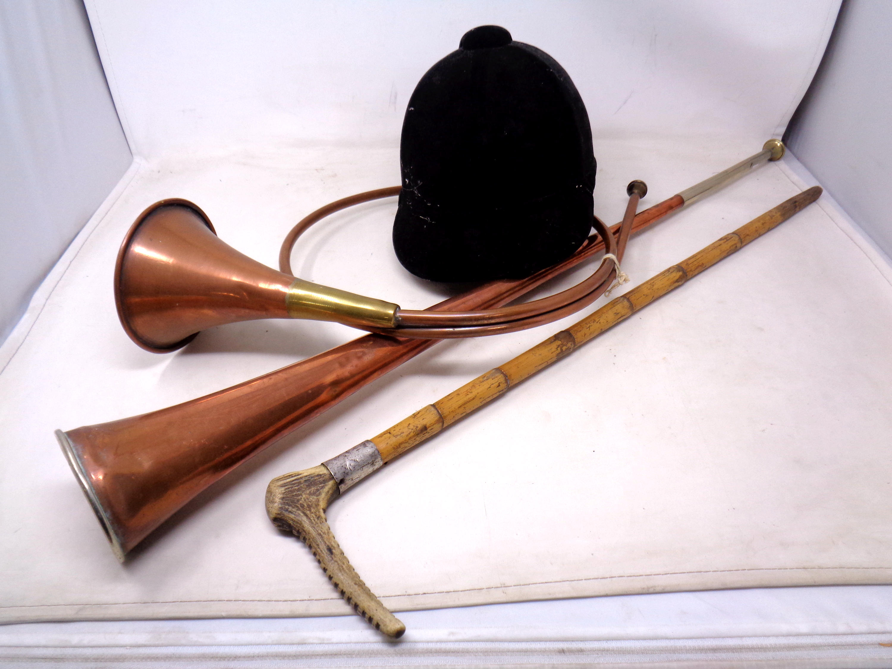 A box containing a riding hat, copper horns and a riding stick.