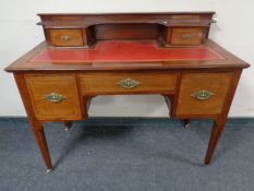 An Edwardian inlaid mahogany knee-hole writing desk on raised legs with a red leather inset panel.