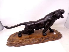 A Japanese patinated metal figure of a tiger on carved wooden plinth (length 46cm).