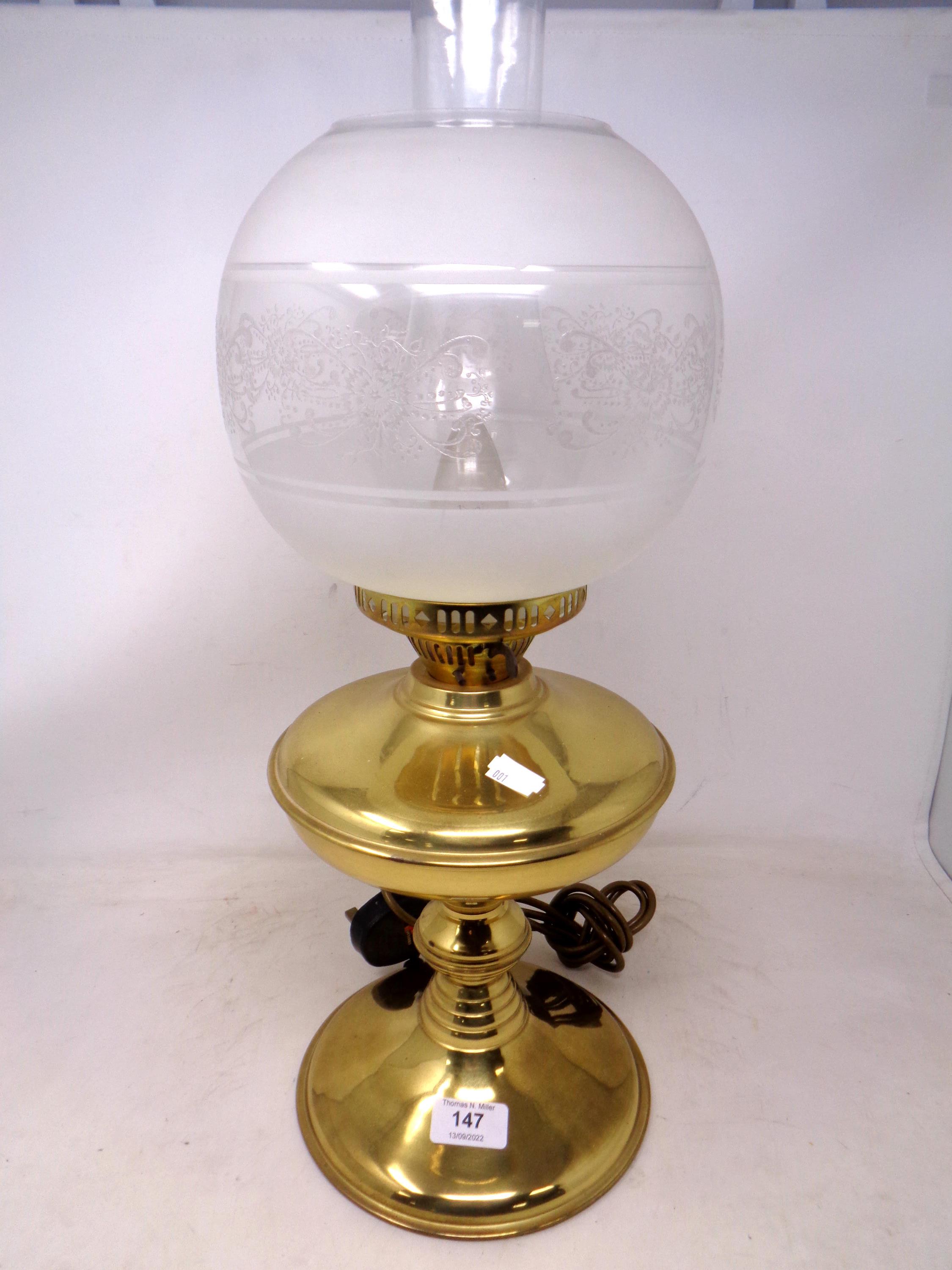 A brass table lamp in the form of an oil lamp with etched glass shade.